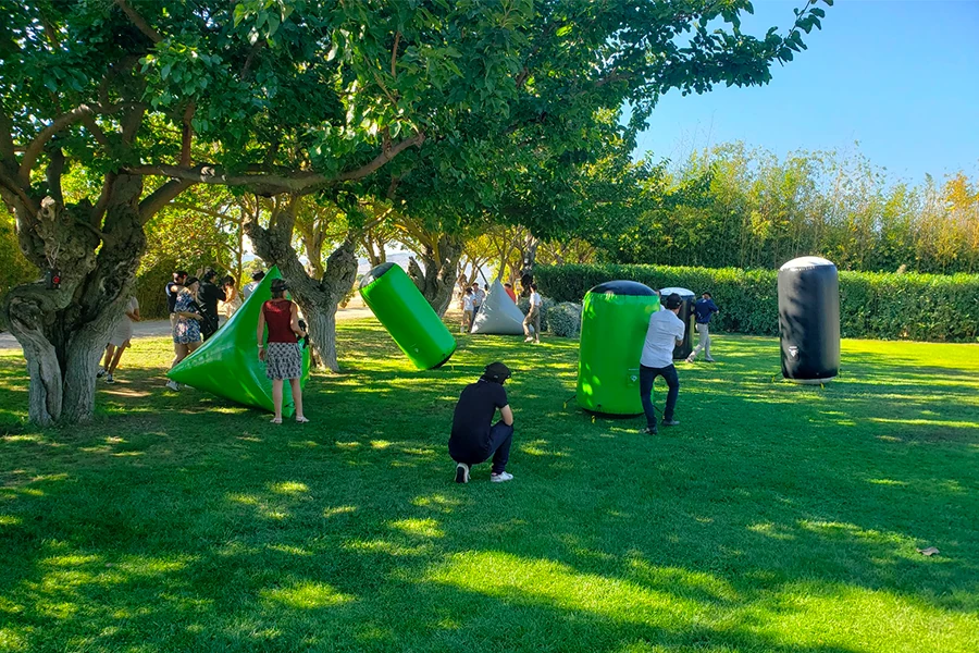 Joueurs accroupis derrière des obstacles gonflables verts lors d'un laser game en plein air
