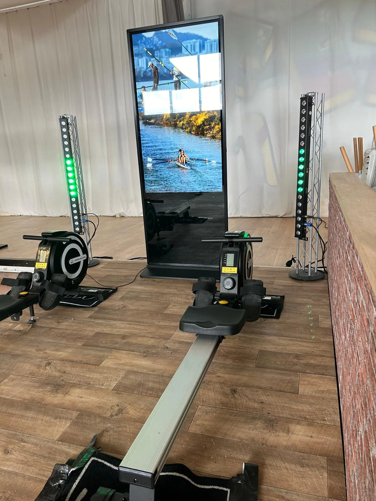 Deux ergomètres et un totem vidéo encadrés par des barres LED dans une salle de réception