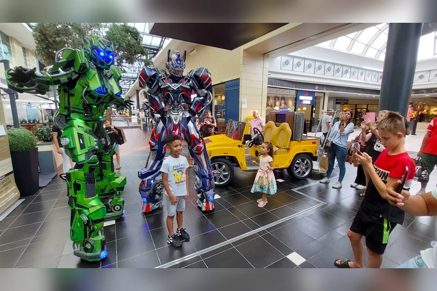 Deux robots LED avec enfants autour d’une voiturette en galerie marchande
