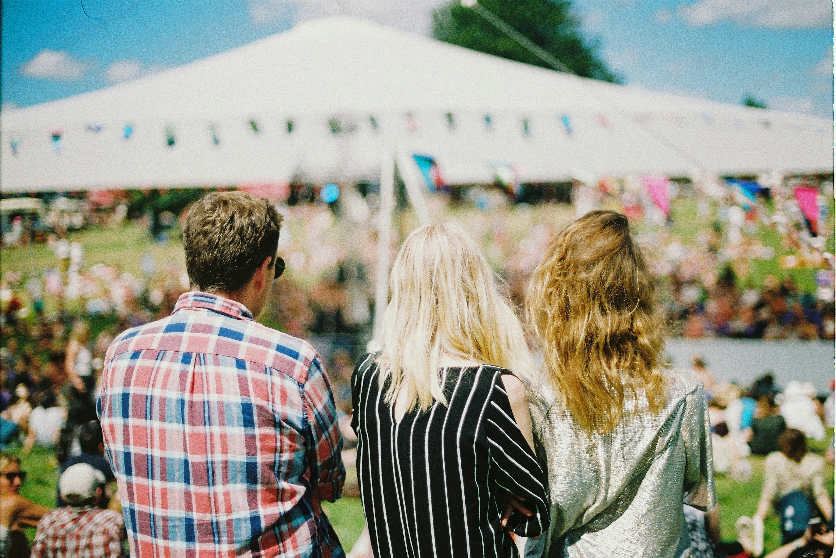 Des visiteurs de dos déambulant dans une kermesse animée