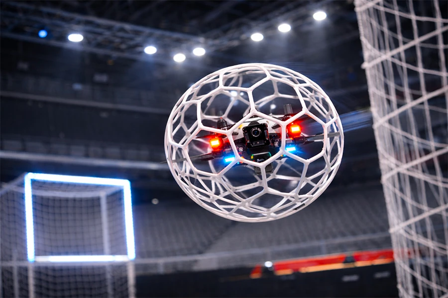 Drone soccer en vol avec sa cage sphérique de protection dans une arène