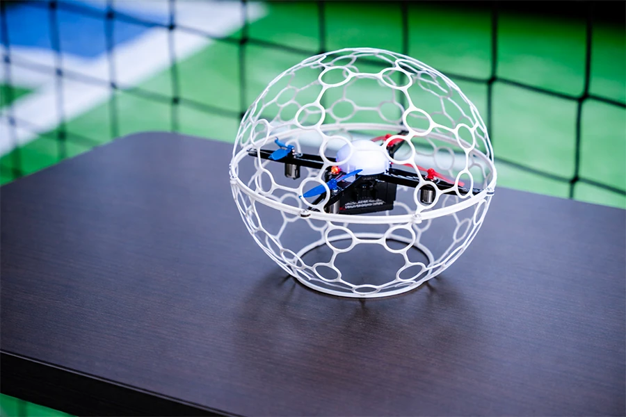 Drone soccer posé sur une table devant les buts lumineux de l'arène