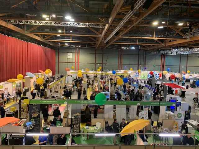 Allées et stands animés d'un salon professionnel vus en hauteur