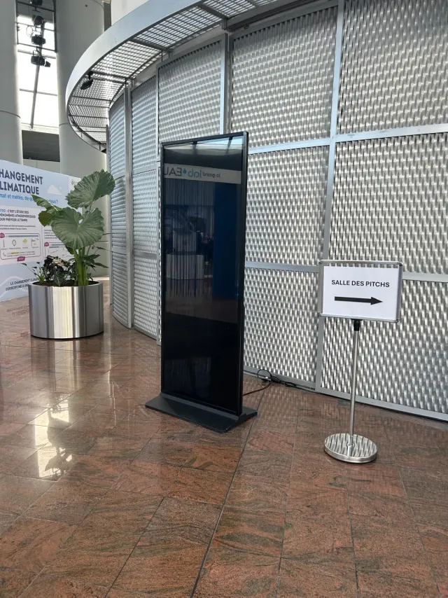 Totem numérique à écran vertical installé dans le hall d'un centre de congrès