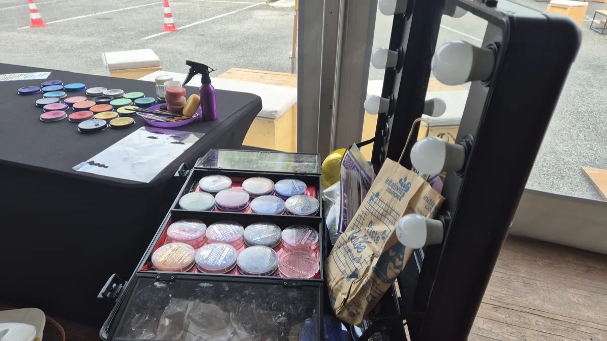 Palettes de fards, pinceaux et miroir de loge lumineux sur la table du stand