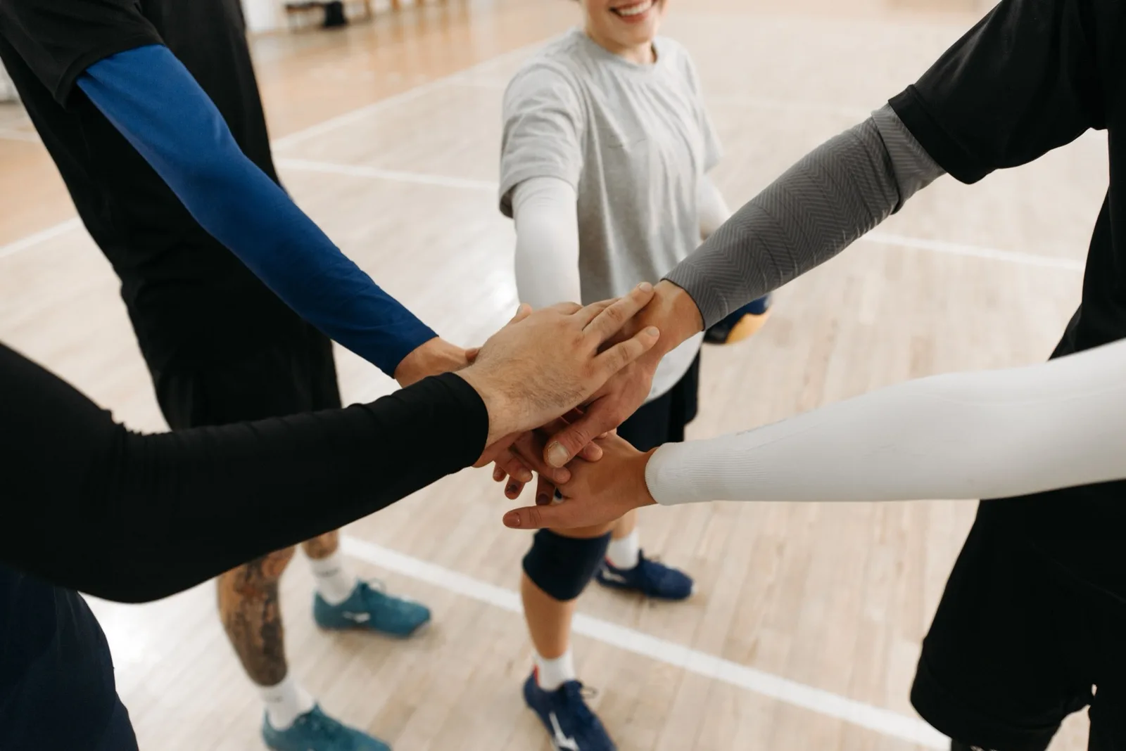 Équipiers joignant leurs mains au centre du cercle avant un défi sportif en gymnase